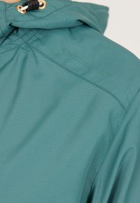 Teal jacket met een gestructureerde afwerking, voorzien van een capuchon, verstelbare trekkoord en een reliëf merklogo "ENDURANCE" op de schouder.