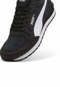 Baskets noires Puma avec bande et logo blancs, dessus en mesh et daim, lacets noirs, semelle intermédiaire blanche et semelle extérieure noire.