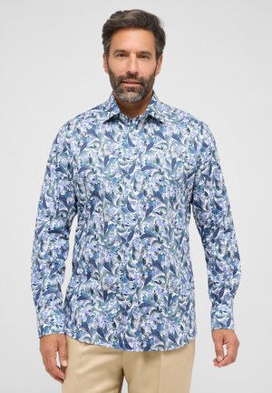 Langarmshirt met een blauw en groen bloemenpatroon op een witte achtergrond. Gemaakt van zachte stof met een puntige kraag.