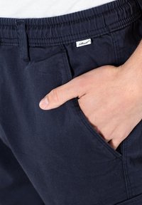 Marineblaue Baumwollshorts mit Kordelzugbund und Seitentaschen, ausgestattet mit dezenten Nähten und einem kleinen Markenetikett am Bund.