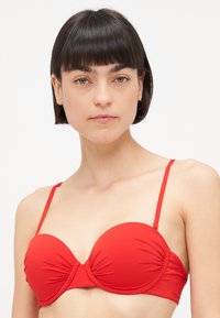 Rdeča bikini zgornji del z strukturiranim, podloženim dizajnom. Ima nastavljive naramnice in nabran tekstilni detajl na sredini za slog in udobje.