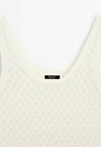 Débardeur en maille beige clair avec un motif en losange, larges bretelles et encolure côtelée. Étiquette intérieure indiquant "Massimo Dutti".