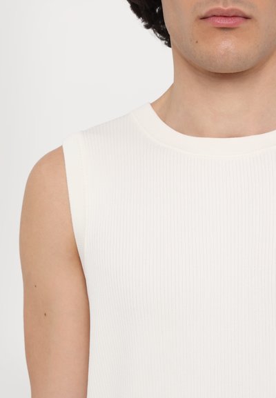 Weißes, geripptes, ärmelloses Oberteil mit Rundhalsausschnitt, das eine glatte Textur und minimale Nähdetails aufweist.