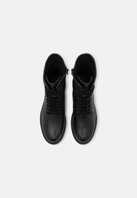 Černé kotníkové kožené boty na šněrování s hladkou texturou a bočním zipem pro snadné obouvání. Kulatá špička a nízkoprofilová gumová podrážka.