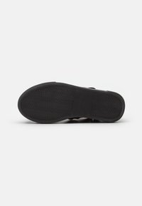Talpa de pantof din cauciuc negru cu un model de prindere în zigzag. Design plat și suprafață netedă, având un stil minimalist și fără accente suplimentare.