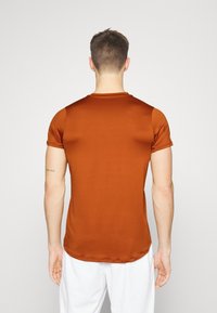 Kortärmad, orange t-shirt med en mjuk textur och rund hals. Baksidan har en figurnära design med en subtil glans.