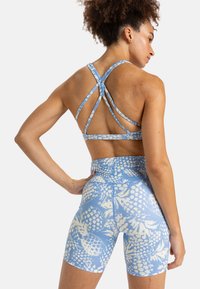 Soutien-gorge de sport à motif bleu avec des bretelles croisées, associé à un short taille haute présentant un design d'ananas en blanc et bleu clair.