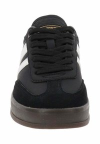 Zapatilla negra con un upper texturizado, rayas laterales blancas, puntera redonda y una suela de goma oscura. Los cordones son negros y están bien ajustados.