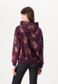 Hanorac bordeaux cu un design floral, dotat cu glugă, manșete și tiv cu nervuri; realizat dintr-o țesătură moale și texturată.