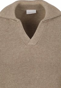 Beige gebreide pullover met een geribde textuur, voorzien van een V-hals ontwerp en een opgevouwen kraag. Label zichtbaar binnen de halslijn.