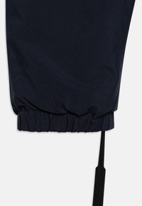 Marineblå joggebukser har elastisk stramming i kanten og en stilren snor. Stoffet ser glatt ut med en matt finish og minimale sømdetaljer.