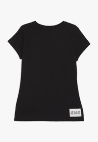 Czarny krótki rękaw T-shirt wykonany z bawełny, z okrągłym dekoltem i białą metką "JEANS" na dolnym prawym boku.