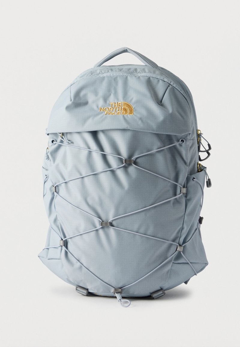 Ανοιχτό μπλε σακίδιο με εμπρός ελαστικό δίχτυ κορδονιού, επάνω λαβή, πλαϊνές τσέπες και κίτρινο κεντημένο λογότυπο The North Face στο μπροστινό μέρος.
