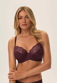 Ciemnofioletowy stanik z drutem podtrzymującym, ozdobiony koronką na miseczkach, wykonany z gładkiego materiału, z regulowanymi ramiączkami i zapięciem na haftek z tyłu.