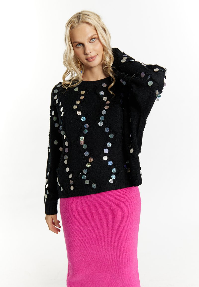 Pulover negru cu embellishementi colorati din paiete, asortat cu o fustă tricotată roz. Puloverul are o croială lejeră și texturi distinctive.