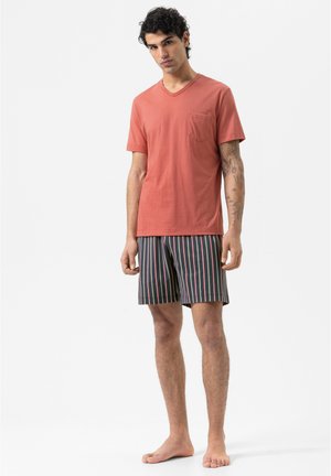 T-shirt V en coton orange avec poche, associée à un short noir et à rayures vertes, roses et bleues. Tissu doux, coupe décontractée.