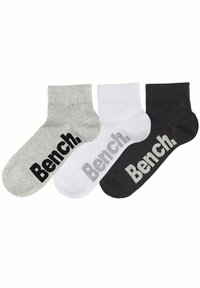 Kolme paria nilkkasukkia harmaana, valkoisena ja mustana, jokaisessa on kontrastivärillä teksti "Bench." sivussa.