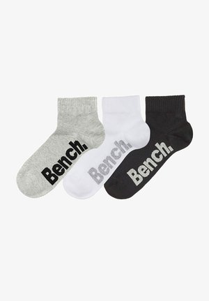 Drei Paar Knöchelstrümpfe in Grau, Weiß und Schwarz, jeweils mit dem Text "Bench." in kontrastierenden Farben an der Seite.