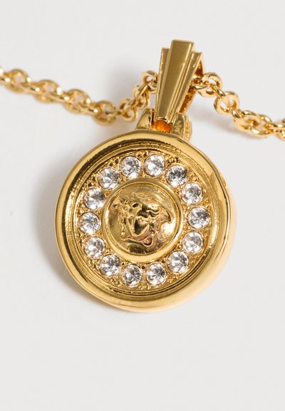 Collier avec pendentif rond en or, tête de lion en relief au centre entourée d’un cercle de pierres précieuses claires sur une chaîne en or.