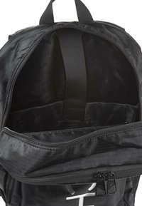 Mochila negra con una parte superior con cremallera y un bolsillo frontal. Presenta dos tiradores de cremallera y una correa interior para asegurar los objetos. Textura de tela suave.