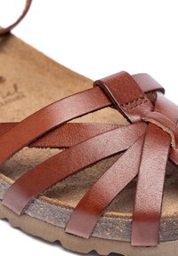 Sandalo in pelle marrone con più fasce larghe, suola in sughero e una soletta testurizzata. Dettaglio della fascia regolabile in evidenza.
