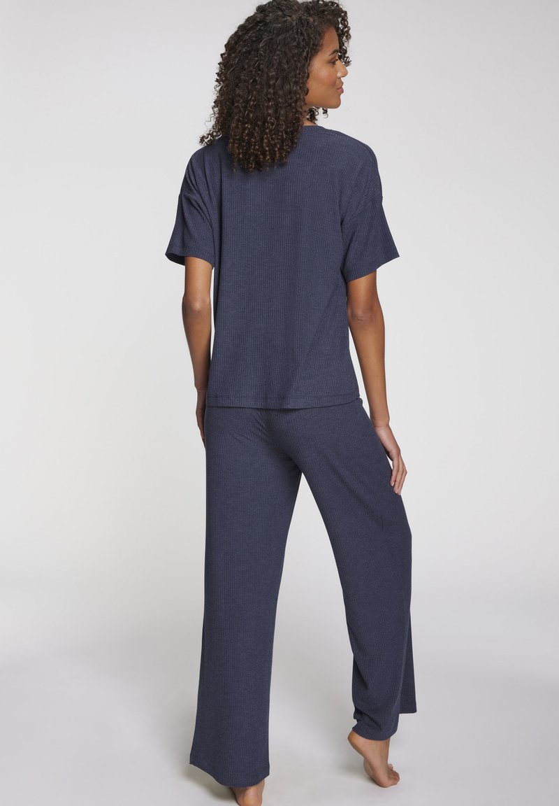 Temno modri komplet udobne obleke, ki vključuje kratkosleeven zgornji del ohlapnega kroja z rebrastim teksturo in široke hlače, oboje izdelano iz mehkega materiala.