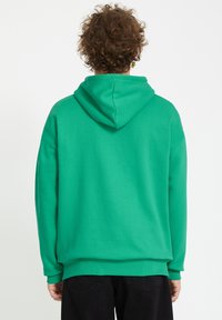 Groene hoodie van zacht materiaal, met een trekkoord in de capuchon, ribgebreide manchetten en zoom. Het ontwerp is van een comfortabele pasvorm en heeft een effen kleur.