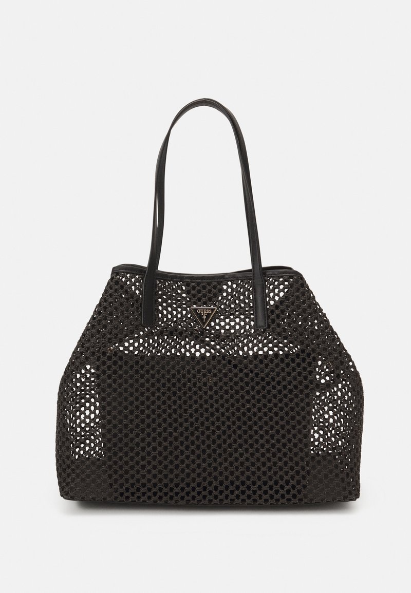 Sac cabas en mesh noir avec poignées en cuir et un logo Guess triangulaire au centre avant sur fond blanc.