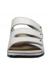White sandal featuring three adjustable straps, an open toe design, a padded footbed, and contrasting black stitching along the sole.