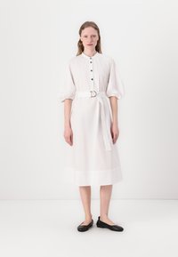 Hvit midi-kjole med krage, knappestolpe foran og korte pufferm; innsnevret midje med stoffbelte, glatt tekstur og minimalistisk design.