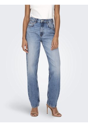 Mujer con vaqueros de tiro alto y pierna recta en azul claro combinados con sandalias de tacón alto en nude y una camiseta sin mangas blanca.