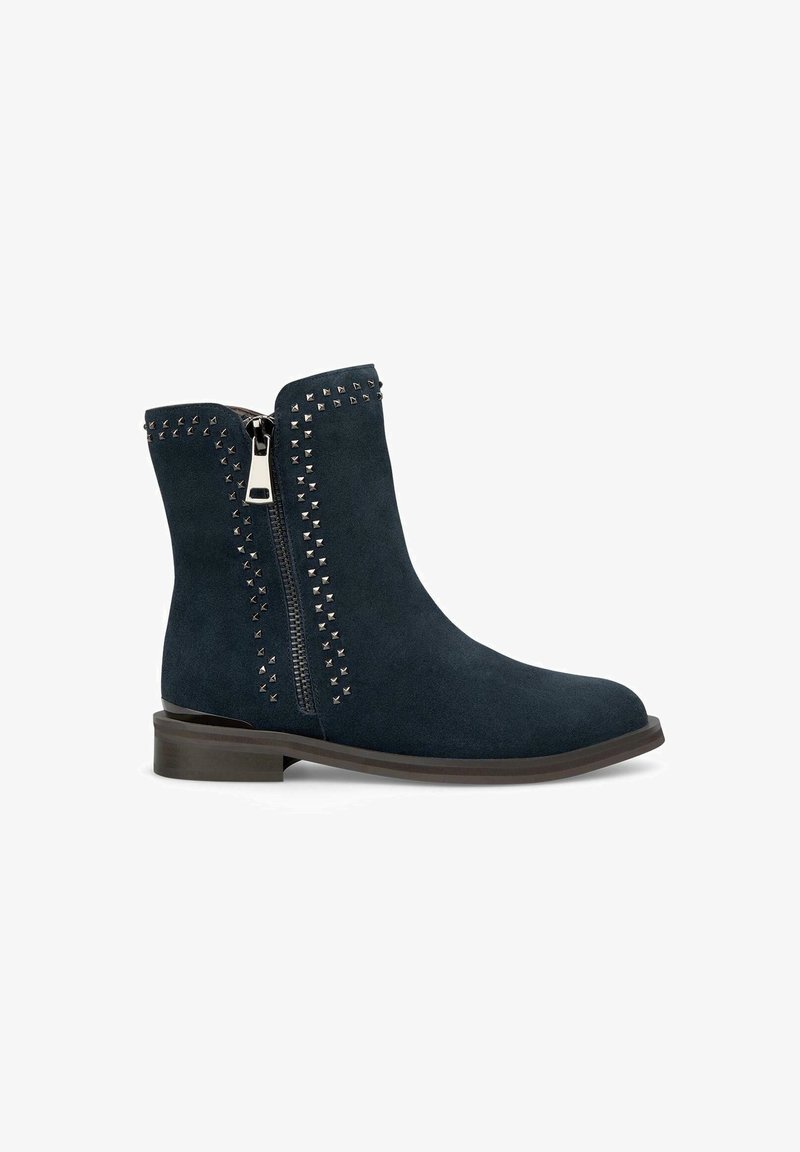 Navyblauwe suède enkellaarzen met een zijrits en metalen studs langs de ritslijn en bovenkant. Lage, platte bruine hak.