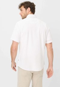 Korte mouwen witte shirt van lichtgewicht stof, met een klassieke kraag en een afgeronde zoom, zichtbare stiksels op de schouders.