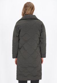 Szürke steppelt kabát magas gallérral, hullámos mintával és hosszú ujjal. A hátsó nézet bemutatja térd hosszúságú kialakítását és sima textúráját.