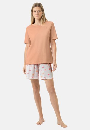 T-shirt en coton pêche à manches courtes associé à un short blanc orné de motifs floraux roses et de pois orange. Design simple, coupe décontractée.