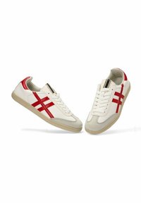 Zapatillas de cuero blancas con detalles rojos y diseño a rayas. Cuentan con una puntera de ante beige y una suela texturizada para ofrecer agarre. Cierre con cordones.