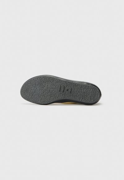Suela de zapato de goma negra con una superficie texturizada y un talón redondeado con un ligero acento amarillo en el borde.