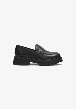 Schwarze Lederloafers mit einer niedrigen, klobigen Sohle. Sie verfügen über eine glatte Oberfläche und eine erhabene Nahtdetails an der Zehenpartie. Mit einem Schlupfdesign.