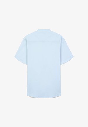 Chemise bleu clair à manches courtes avec col, présentant une coupe droite et une texture lisse et tissée. Aucun motif ni accent visible.