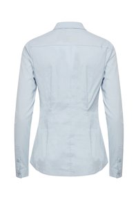 Chemise ajustée à manches longues bleu clair avec col, poignets à boutons et coutures visibles dans le dos pour la mise en forme.