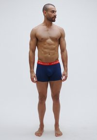 Cuecas boxer masculinas azul marinho com cós elástico vermelho rotulado "JACK & JONES." Tecido leve, design ajustado, sem padrões visíveis.