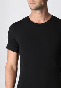 T-shirt nera a maniche corte con scollatura rotonda, realizzata in tessuto liscio, con un design aderente e senza loghi o motivi visibili.