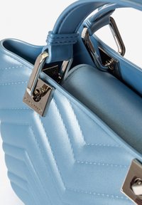 Lichtblauwe handtas van nepleer met een gewatteerd chevronpatroon. Voorzien van zilverkleurige hardware en dubbele handgrepen voor draaggemak.