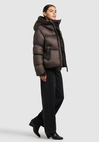 Tumeroheline läikiva viimistlusega puffer-jope, üle suurendatud kapuuts ja esitaskud. Sobitatud kõrge vöökohaga mustade teksade ja kontsakingadega.