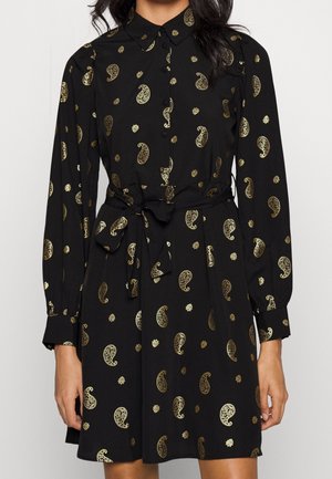 Czarna sukienka z długim rękawem ozdobiona złotymi wzorami paisley i motywami słonecznymi, zapinana na guziki z kołnierzykiem i paskiem wiązanym w talii.