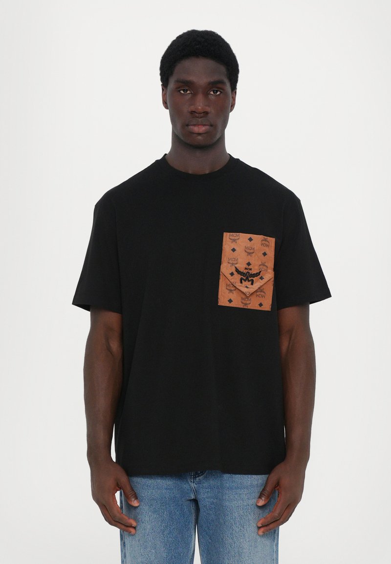 T-shirt noir en coton avec une poche à motif marron comportant des détails de logo. Manches courtes, col rond et coupe décontractée.