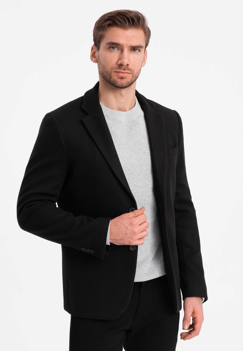 Zwarte blazer van wolblend, enkel-breasted ontwerp met notch revers, gedragen over een lichtgrijze ronde hals trui, met knoopaccenten.