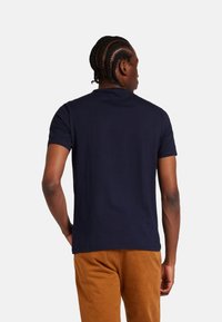 Camiseta de algodón de manga corta en azul marino con cuello redondo. Presenta una textura suave y un corte relajado. Adecuada para el uso casual.