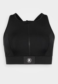 Czarny sportowy crop top z zamkiem błyskawicznym, wyposażony w szeroki elastyczny pas u dołu oraz subtelnym detalem z logo. Gładki, rozciągliwy materiał.