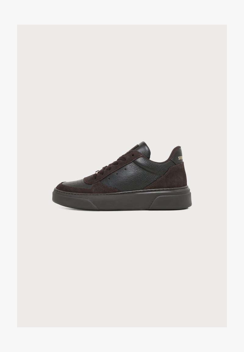 Baskets basses noires avec panneaux en cuir et en daim, lacets à l'avant et semelle épaisse en caoutchouc, vues de profil.